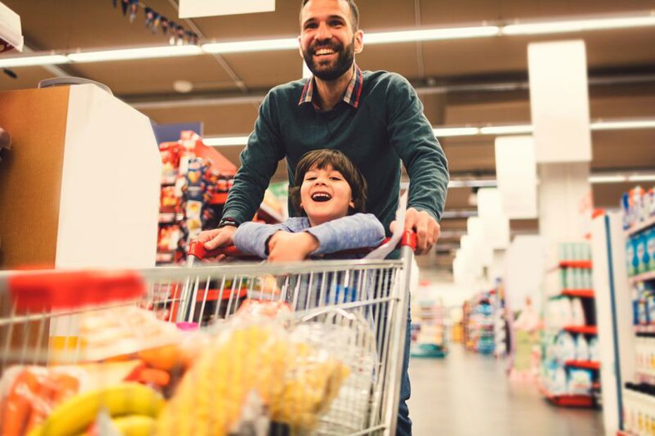 Father and son in grocery store with shopping cart full of groceries