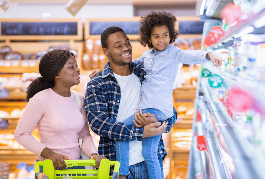 Family of three grocery shopping, a wife, husband and child with a shopping cart